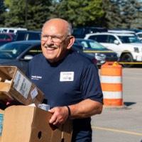 Class of 1967 Alumnus smiles as he carries in 2 cardboard boxes for new lakers